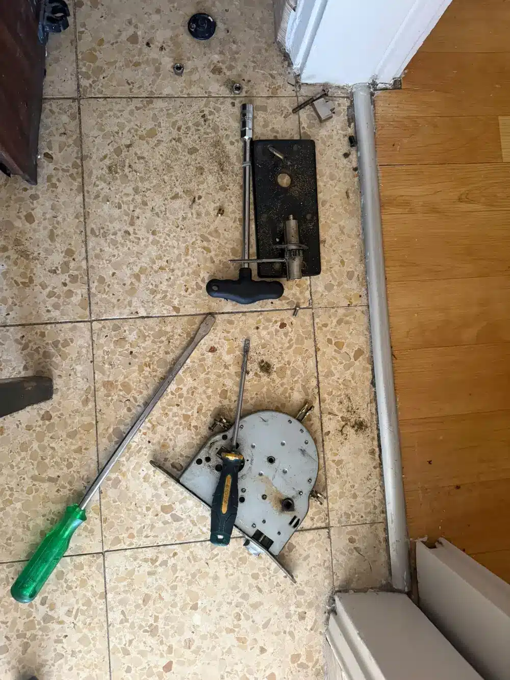 רכיבי המנעול והצילינדר שפורקו מהדלת, לצד כלי העבודה