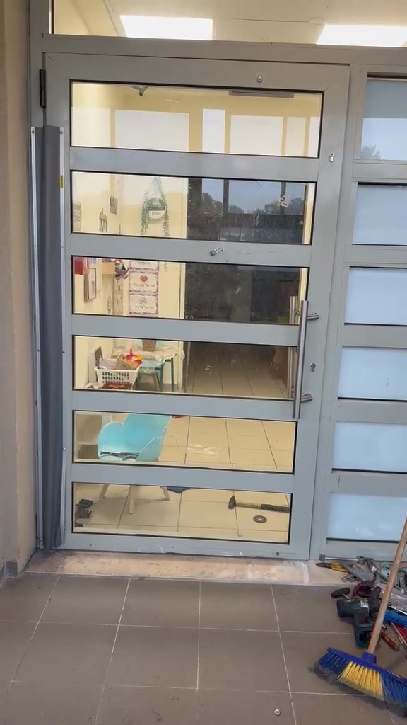 דלת אלומיניום וזכוכית בכניסה לגן ילדים בבאר יעקב, סגורה וישרה במשקוף אחרי ההרמה